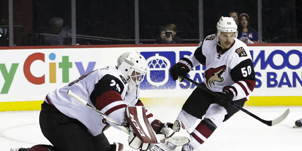 Arizona Coyotes goalie Anders Lindback (29) stops a shot on the goal  as teammate Antoine Vermette ...
