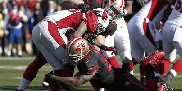 Arizona Cardinals running back Chris Johnson, center, is tackled by San Francisco 49ers linebacker ...