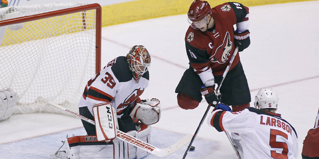 Arizona Coyotes' Shane Doan (19) tries to re-direct the puck past New Jersey Devils goalie Cory Sch...