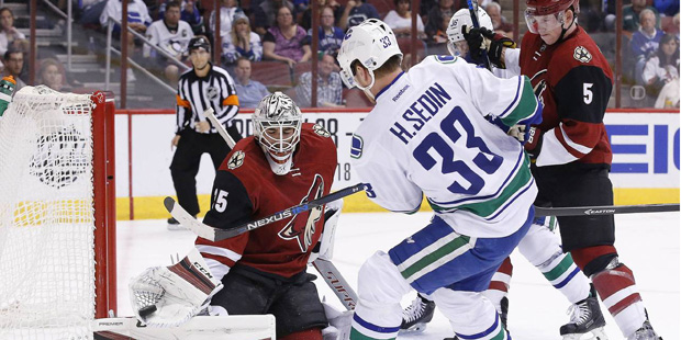 Arizona Coyotes' Louis Domingue, left, makes a save on a shot by Vancouver Canucks' Henrik Sedin (3...