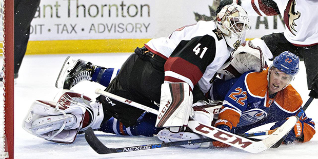 Edmonton Oilers' Adam Cracknell (22) crashes into Arizona Coyotes' goalie Mike Smith (41) during th...