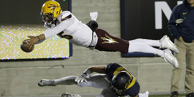 Arizona State quarterback Manny Wilkins dives over California safety Luke Rubenzer after being forc...