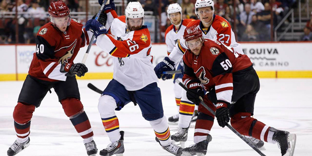 Arizona Coyotes' Antoine Vermette (50) reaches out for the puck as Coyotes' Alex Tanguay (40) and F...