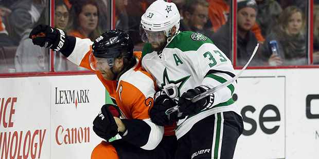 Philadelphia Flyers' Claude Giroux, left, is taken to the boards by Dallas Stars'  Alex Goligoski a...