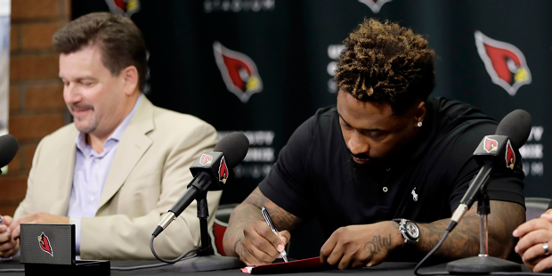 Darnell Dockett sings a contract with the Arizona Cardinals as head coach Bruce Arians, right, and ...