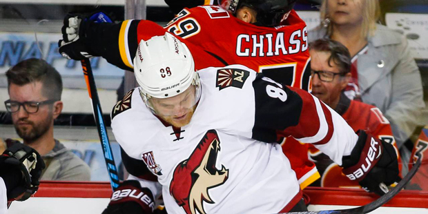Arizona Coyotes' Jamie McGinn, left, checks Calgary Flames' Alex Chiasson during the first period o...