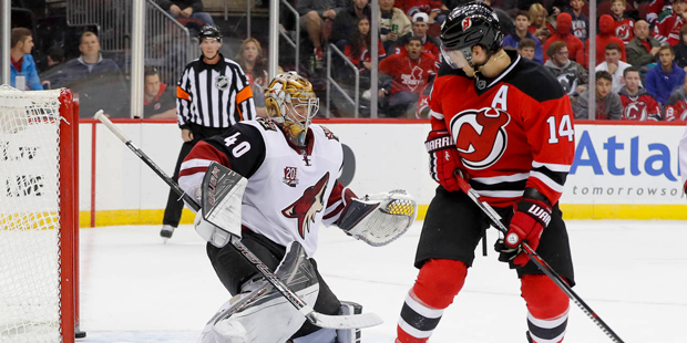 New Jersey Devils center Adam Henrique (14) knocks the puck past Arizona Coyotes goalie Justin Pete...