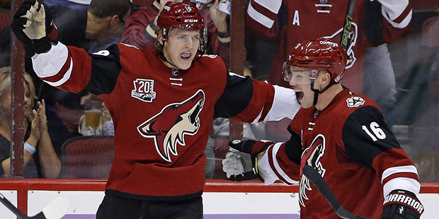 Arizona Coyotes' Christian Dvorak, left, celebrates with teammate Max Domi (16) after Dvorak's firs...