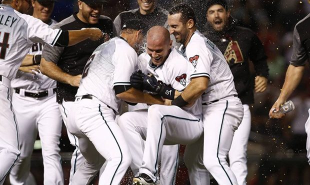 Arizona Diamondbacks' Chris Herrmann, middle, is picked up off the ground by teammates Jeff Mathis ...