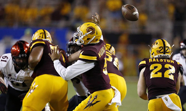 Arizona State's Manny Wilkins, middle, loses control of the football as he tries to throw a pass ag...