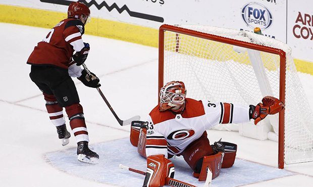 Arizona Coyotes center Clayton Keller, left, scores a shootout goal against Carolina Hurricanes goa...