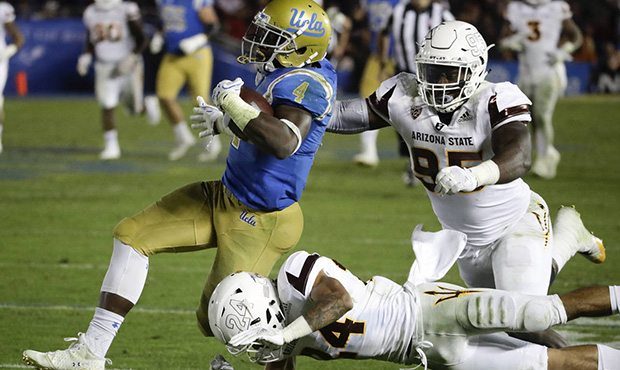 UCLA running back Bolu Olorunfunmi, left, runs past Arizona State defensive lineman Renell Wren, to...