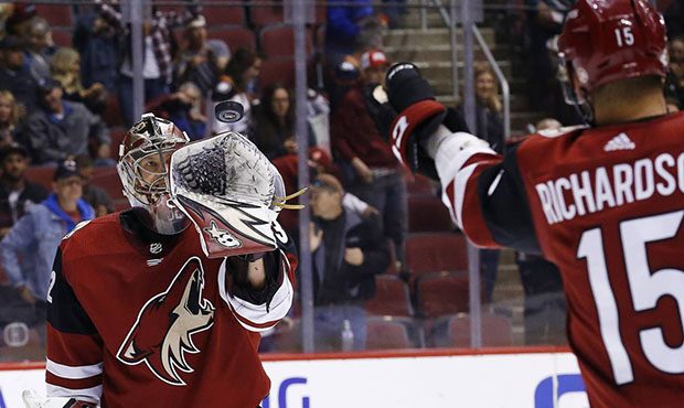 Arizona Coyotes goaltender Antti Raanta, left, reaches out to catch the puck tossed to him by cente...