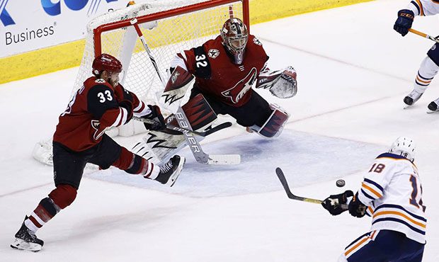 Arizona Coyotes goaltender Antti Raanta (32) and defenseman Alex Goligoski (33) slide over to prote...