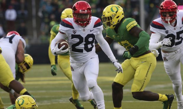 Arizona's Nick Wilson breaks through the Oregon defense for a 18-yard touchdown run in the first qu...