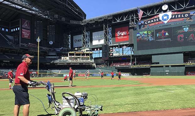 The grounds crew at Chase Field prepares the field prior to a spring training baseball game between...