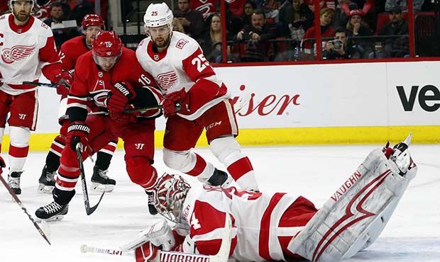 Detroit Red Wings goaltender Petr Mrazek (34) dives for the puck in front of a charging Carolina Hu...