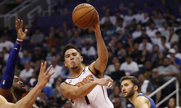 Phoenix Suns guard Devin Booker (1) passes around Dallas Mavericks guard Wesley Matthews (23) durin...