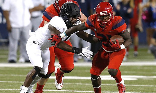 Arizona running back J.J. Taylor (21) stiff arms an Oregon defender in the first half during an NCA...