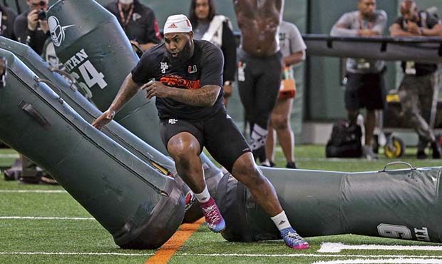 Miami defensive tackle Gerald Willis, front, runs through the tackling dummies as defensive end Joe...