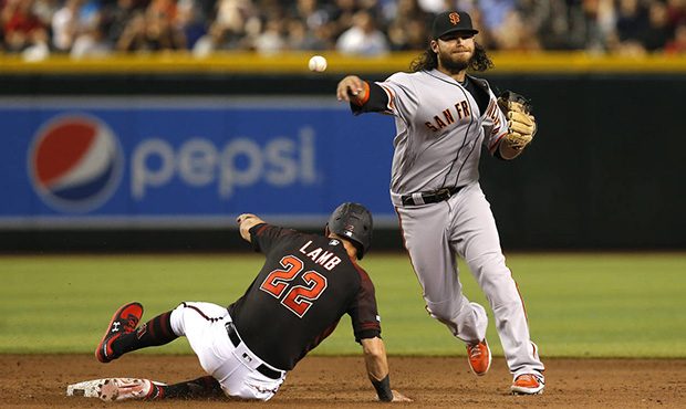 San Francisco Giants shortstop Brandon Crawford, right, turns a double play while avoiding Arizona ...