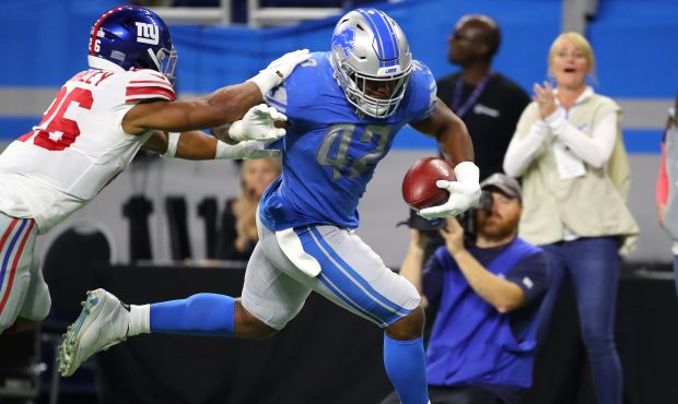 Devon Kennard #42 of the Detroit Lions runs past Saquon Barkley #26 of the New York Giants for a fi...