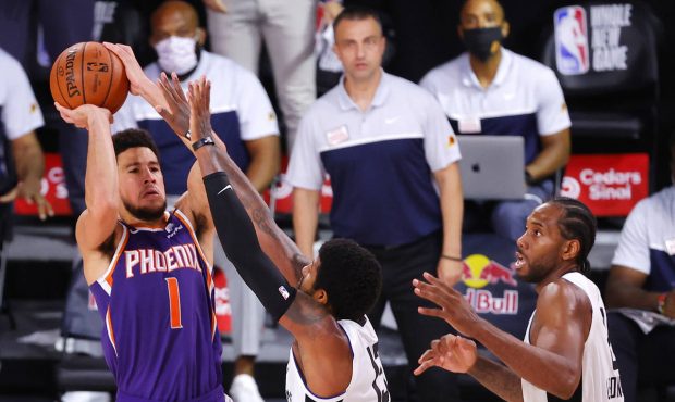 Devin Booker #1 of the Phoenix Suns shoots the game winning basket over Paul George #13 of the LA C...
