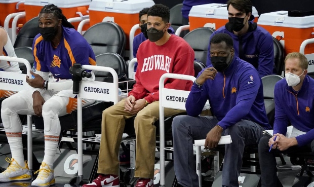 Phoenix Suns guard Devin Booker watches from the bench during the first half of an NBA basketball g...