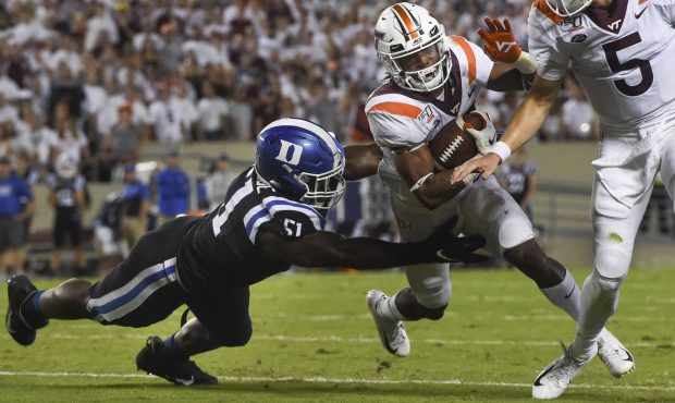 Running back Deshawn McClease #33 of the Virginia Tech Hokies is tackled by defensive end Victor Di...