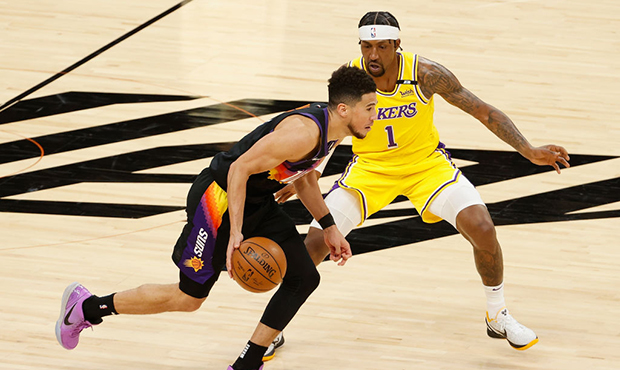 Devin Booker #1 of the Phoenix Suns drives the ball past Kentavious Caldwell-Pope #1 of the Los Ang...