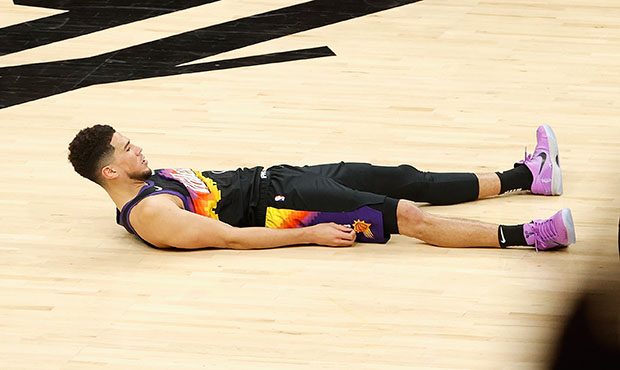 Devin Booker #1 of the Phoenix Suns reacts to a three-point shot and foul from the Denver Nuggets d...