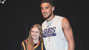 Devin Booker presents young card-collecting fan with jersey before game at Lakers
