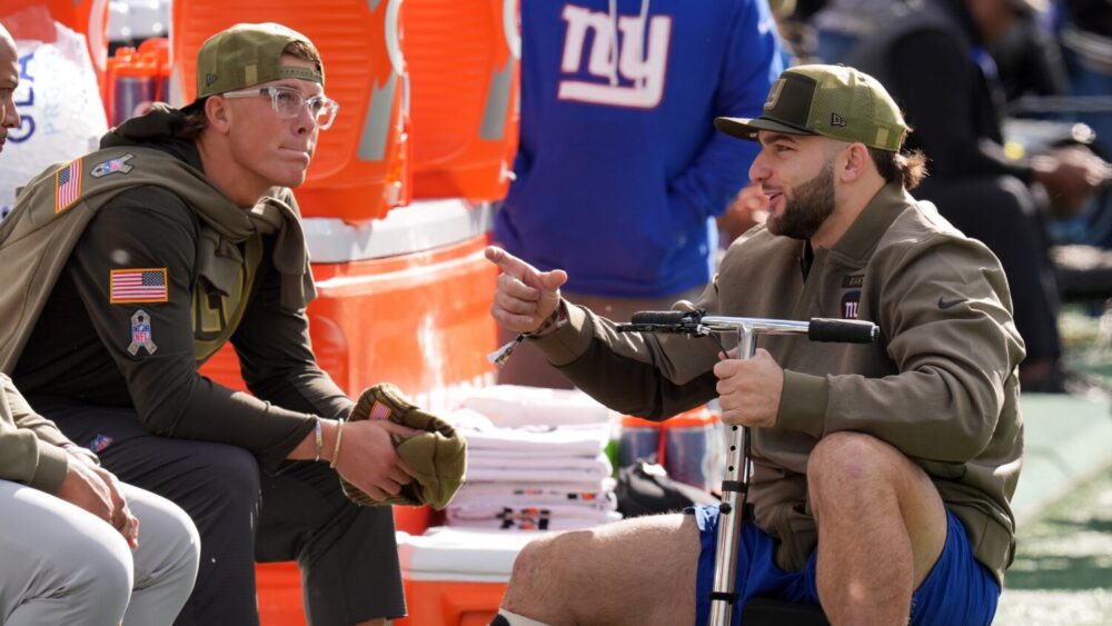New York Giants' injured players Cam Skattebo and Jaxson Dart talk before an NFL football game agai...