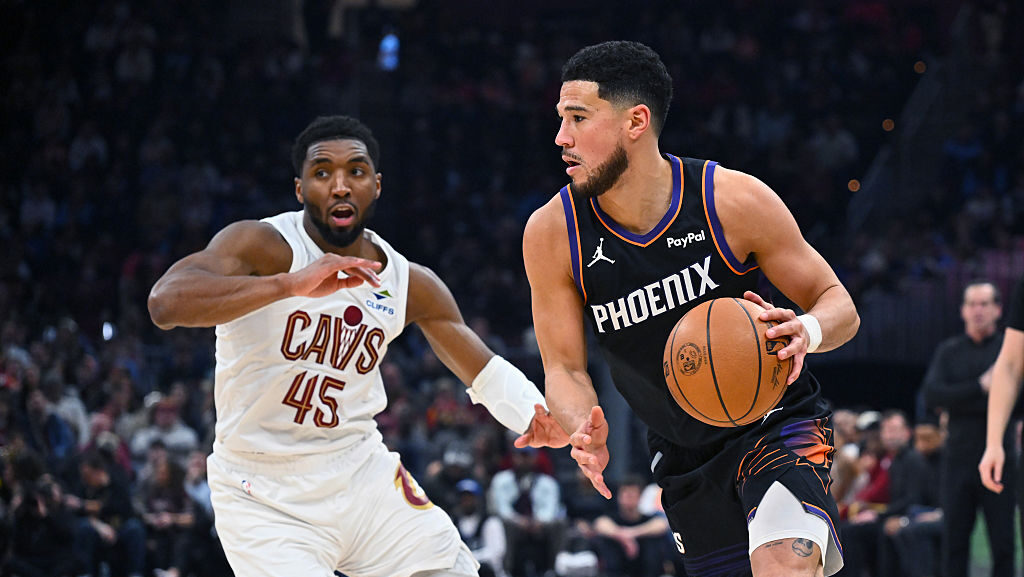 Devin Booker #1 of the Phoenix Suns drives to the basket around Donovan Mitchell #45 of the Clevela...