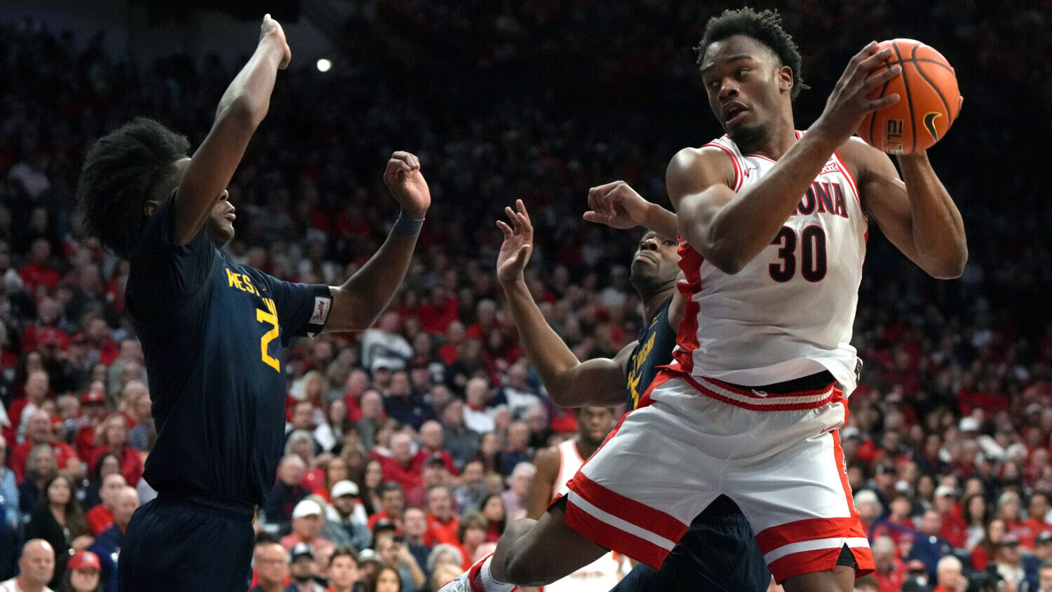 Arizona forward Tobe Awaka drives on West Virginia guard Amir Jenkins (2) and guard Honor Huff duri...
