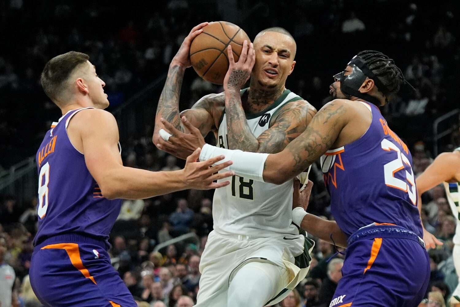 Milwaukee Bucks' Kyle Kuzma (18) drives to the basket between Phoenix Suns' Jordan Goodwin (23) and...