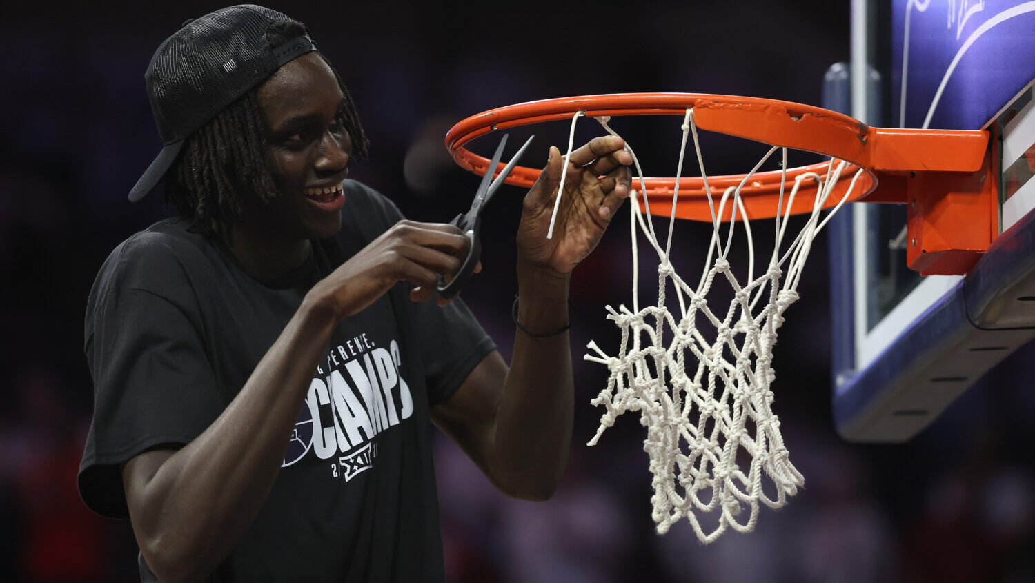Sidi Gueye #15 of the Arizona Wildcats cuts down the nets as he celebrates winning the Big 12 regul...