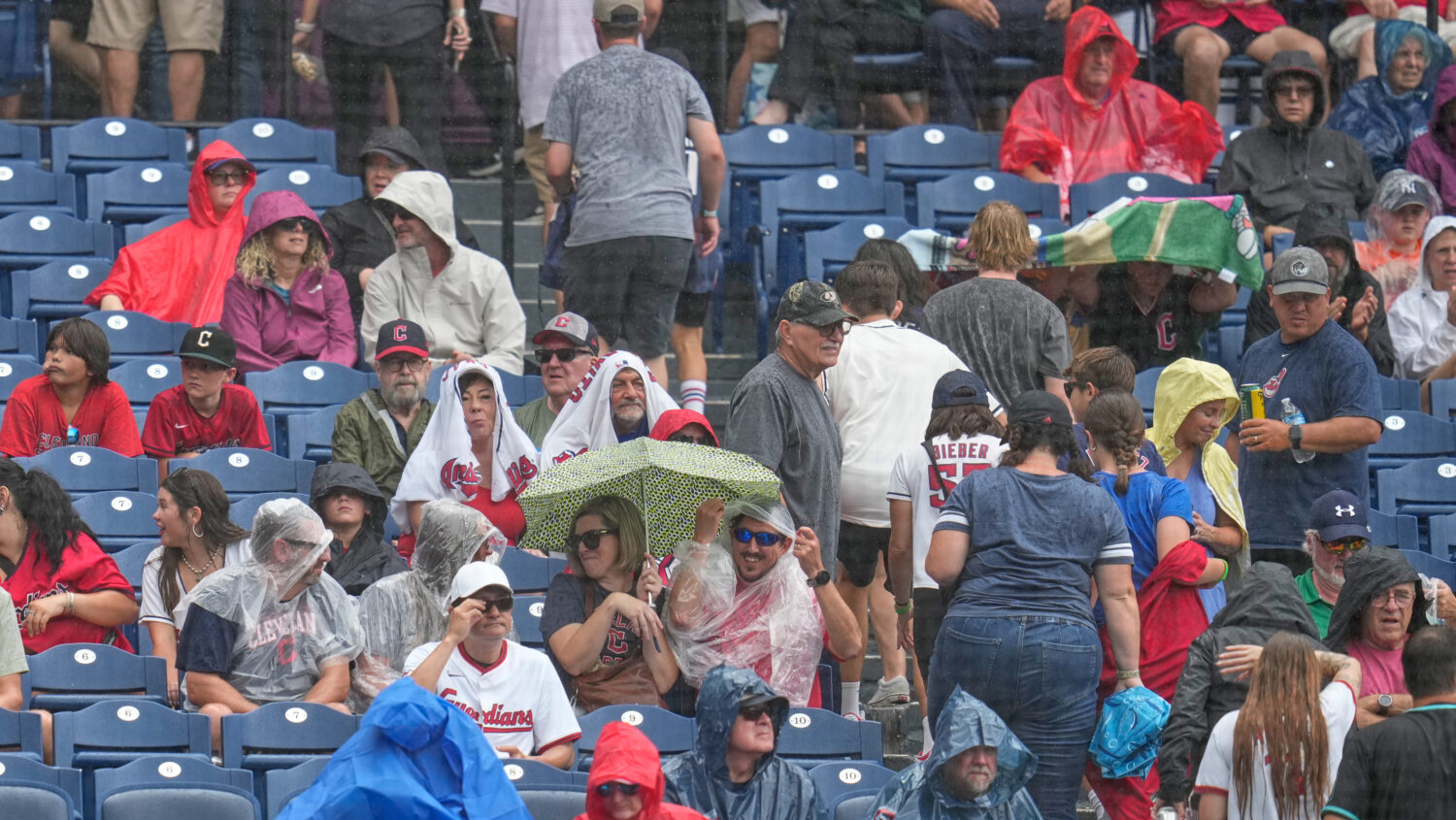 Fans head for cover during a rain shower in the third inning of a baseball game between the Arizona...